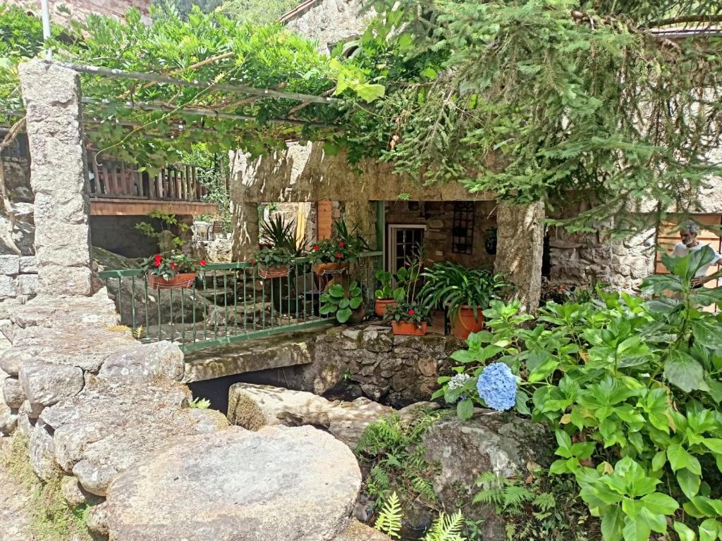 Fachada de piedra del molino con plantas y una pasarela sobre el agua